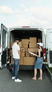 Two delivery workers handing over a package in a warehouse setting.